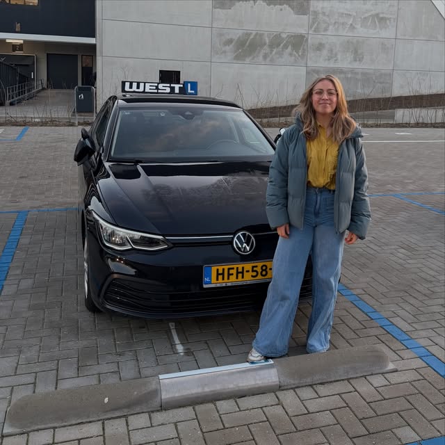 Geslaagde leerling viert haar rijbewijs naast de WEST-lesauto